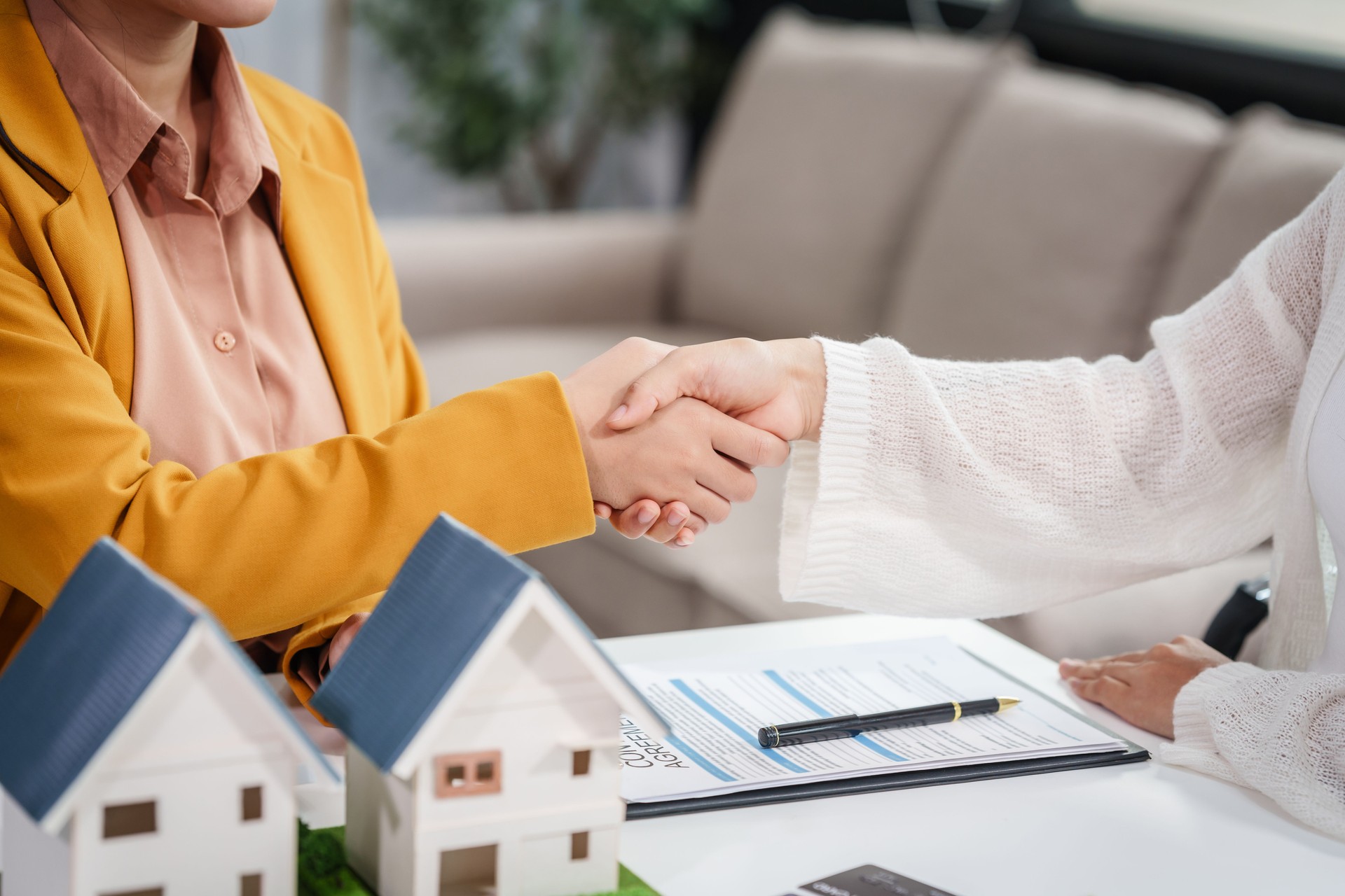 Une femme d’affaires asiatique discute des contrats d’achat de maison avec les clients à son bureau, en se concentrant sur les prêts, les hypothèques et d’autres aspects financiers des transactions immobilières.